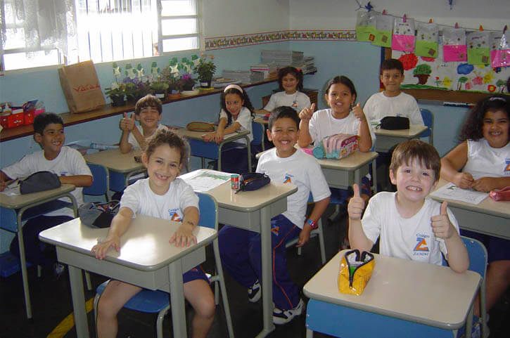 Niños felices en una sala de clase. Les estamos exigiendo a los niños más de lo que deben dar, a costa de su felicidad.